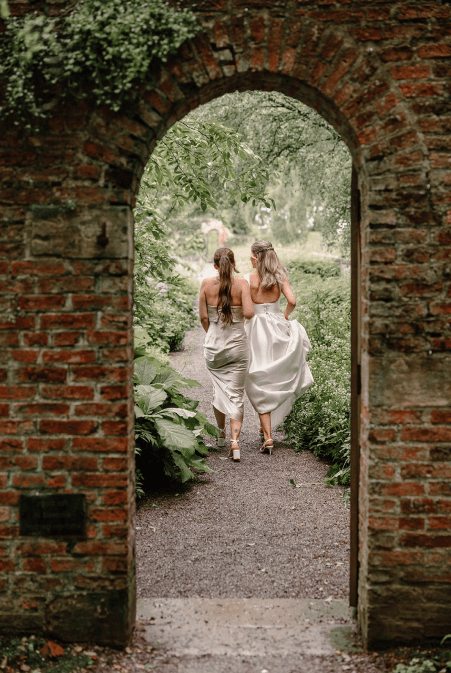 bridal-party-in-garden-at-uk-wedding Candid wedding shot of bridal party walking in garden at UK wedding.